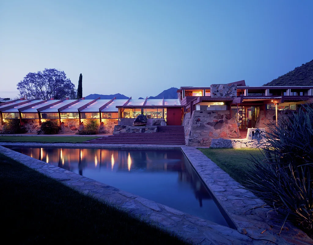 Taliesin West at dusk, with illuminated desert masonry buildings reflected in the pool, photographed by Carol M. Highsmith.